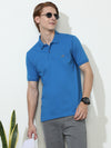 Man wearing a blue solid blue half sleeve casual polo t shirt with casual styling on a gray background