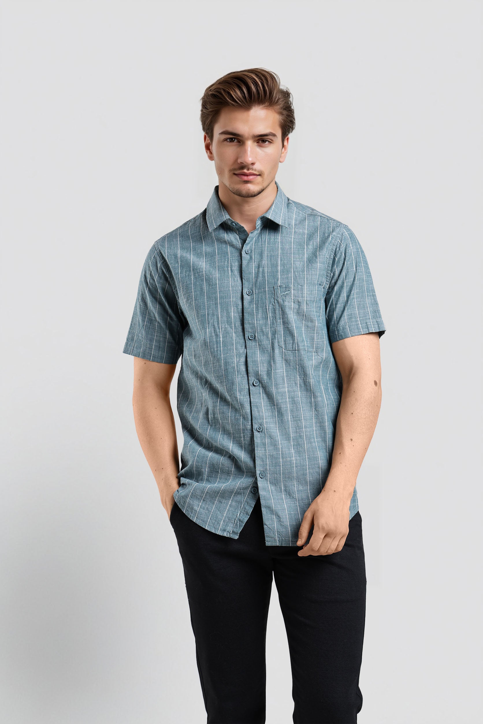 Man wearing a blue checkered shirt and black pants on a light gray background