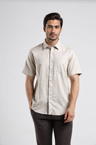 Man wearing a beige short-sleeve shirt against a white background