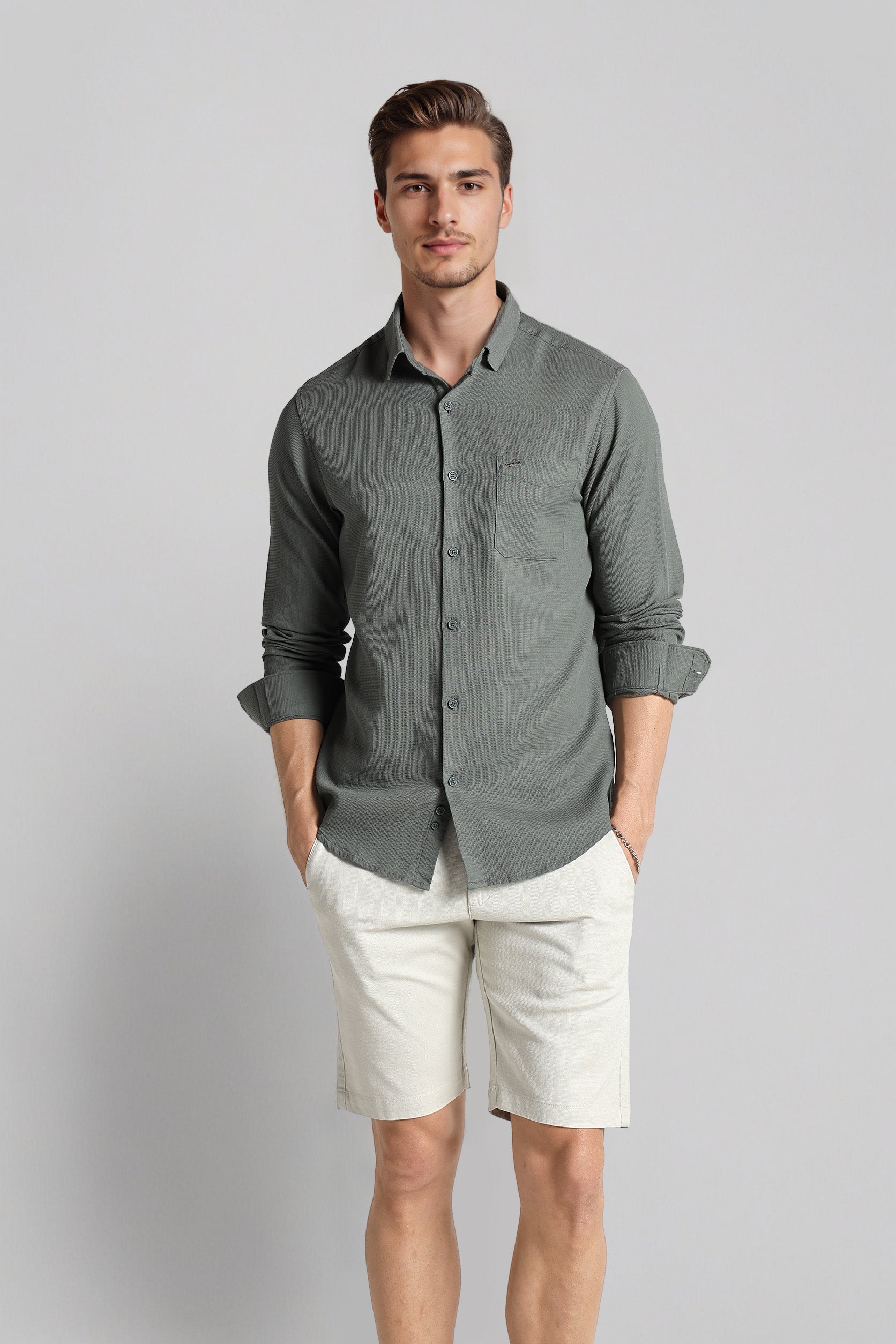 Man wearing a gray button-up shirt and white shorts on a light gray background