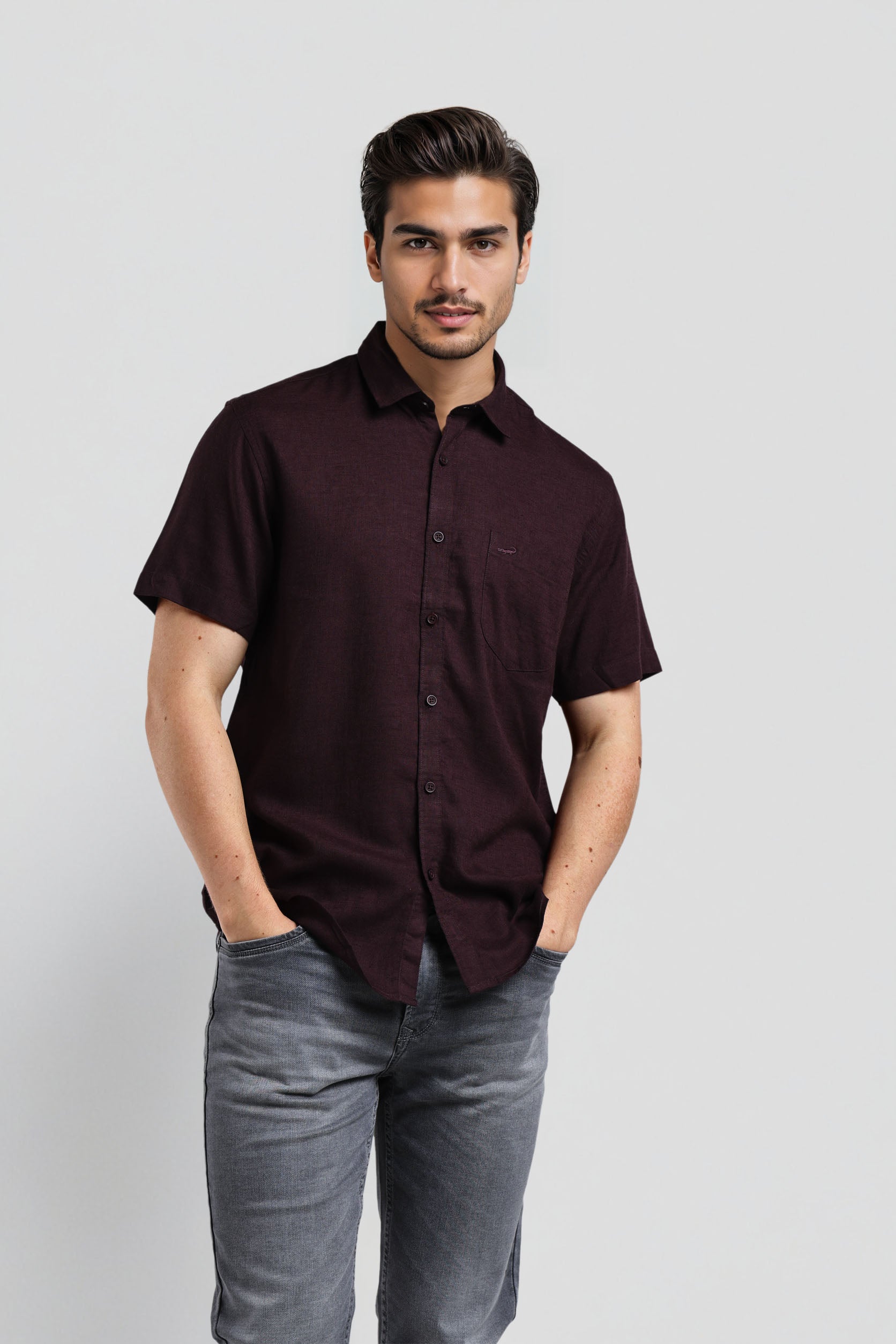 Man wearing a dark brown shirt and gray pants on a white background