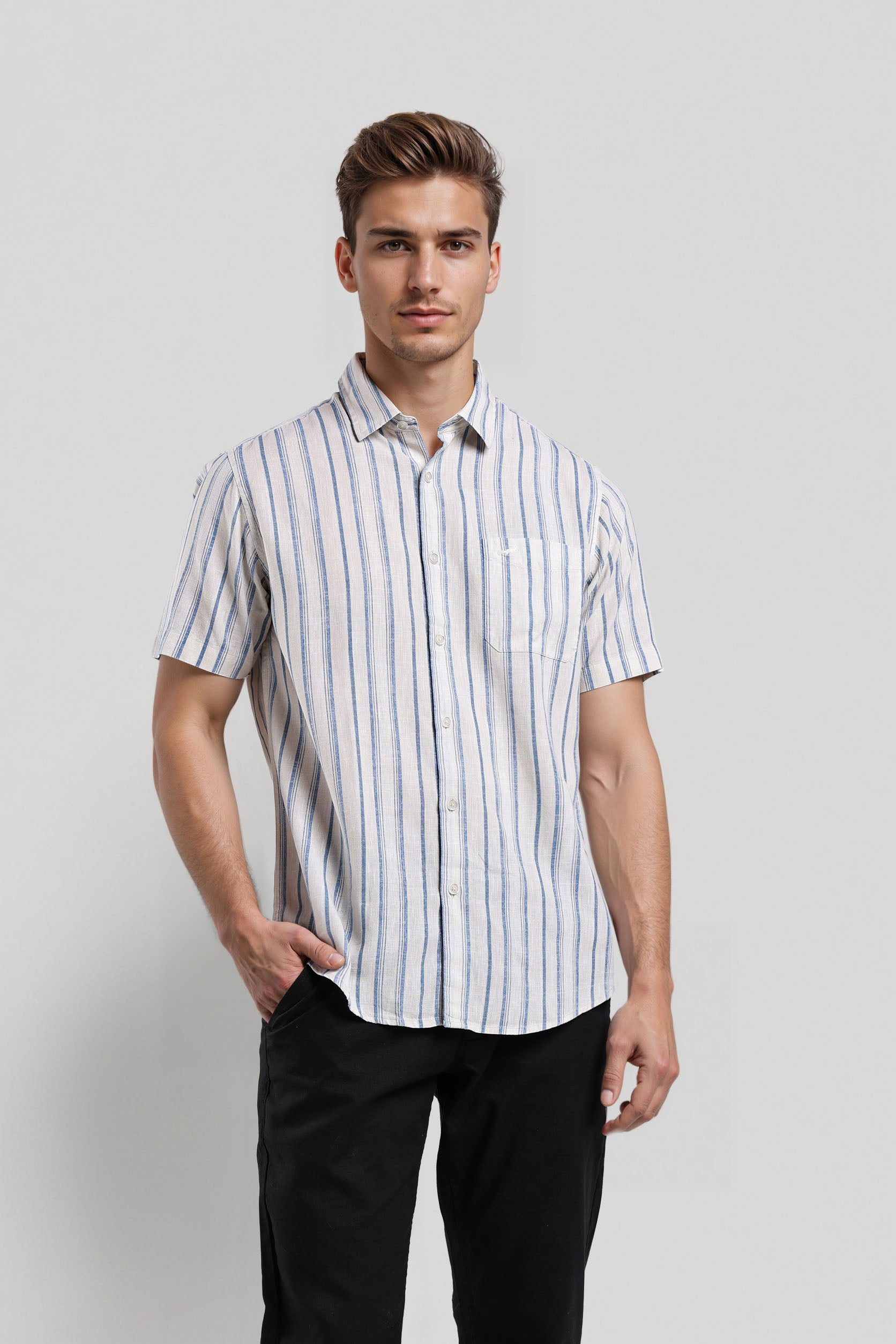 Man wearing a striped shirt and black pants against a plain background