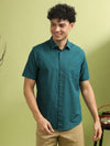 Man wearing a teal solid half sleeve 100% cotton shirt with casual styling on a gray background