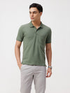 Man wearing a olive olive structure slim fit polo t shirt on a light gray background