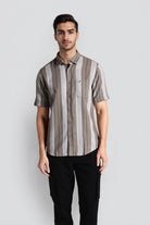 Man wearing a striped shirt and black pants against a plain background