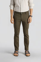 Person wearing olive green pants and a light-colored shirt on a white background