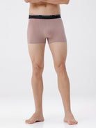 Person wearing a pair of pink boxer briefs with a black waistband on a white background