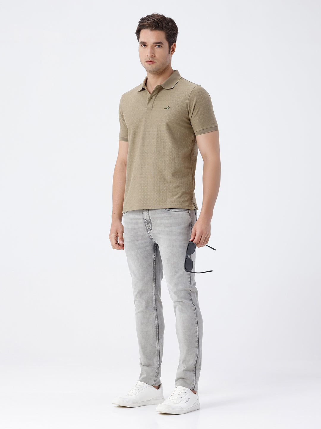 Man wearing a grey light grey knit slim fit jeans on a light gray background
