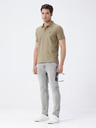 Man wearing a grey light grey knit slim fit jeans on a light gray background