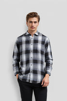 Man wearing a black and gray plaid shirt against a light gray background