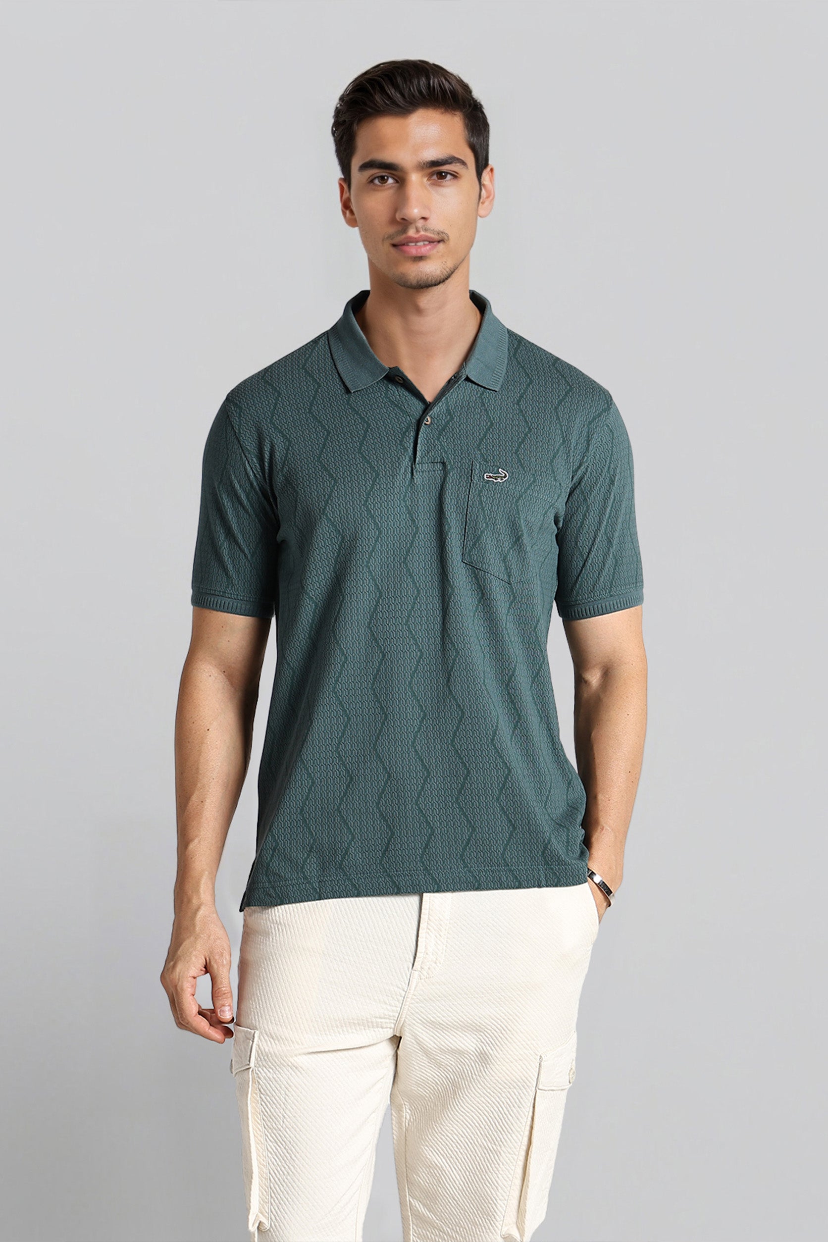 Man wearing a green textured polo shirt with a logo on a gray background