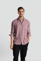 Man wearing a pink shirt and black pants on a white background