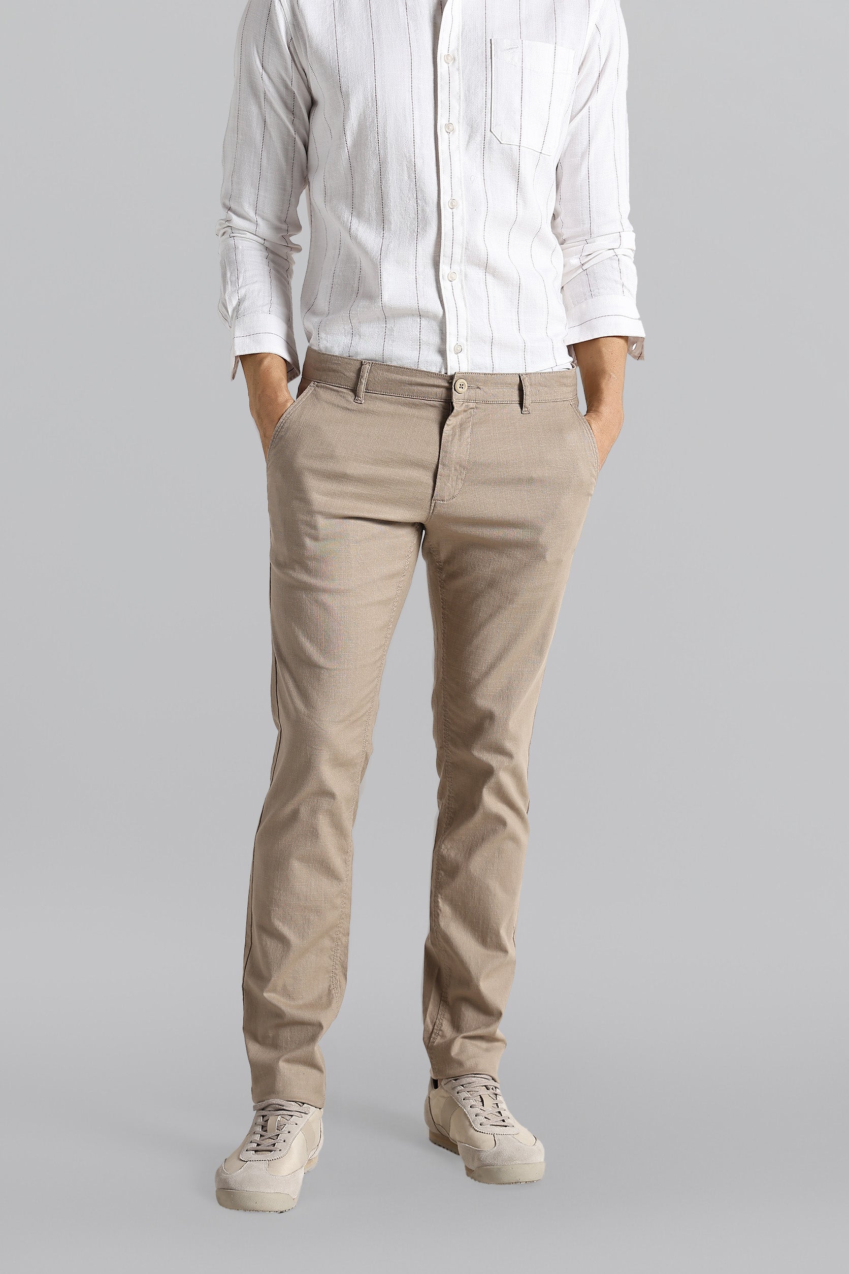 Person wearing a white shirt and beige pants on a gray background