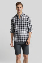 Man wearing a black and white checkered shirt and gray shorts on a light gray background