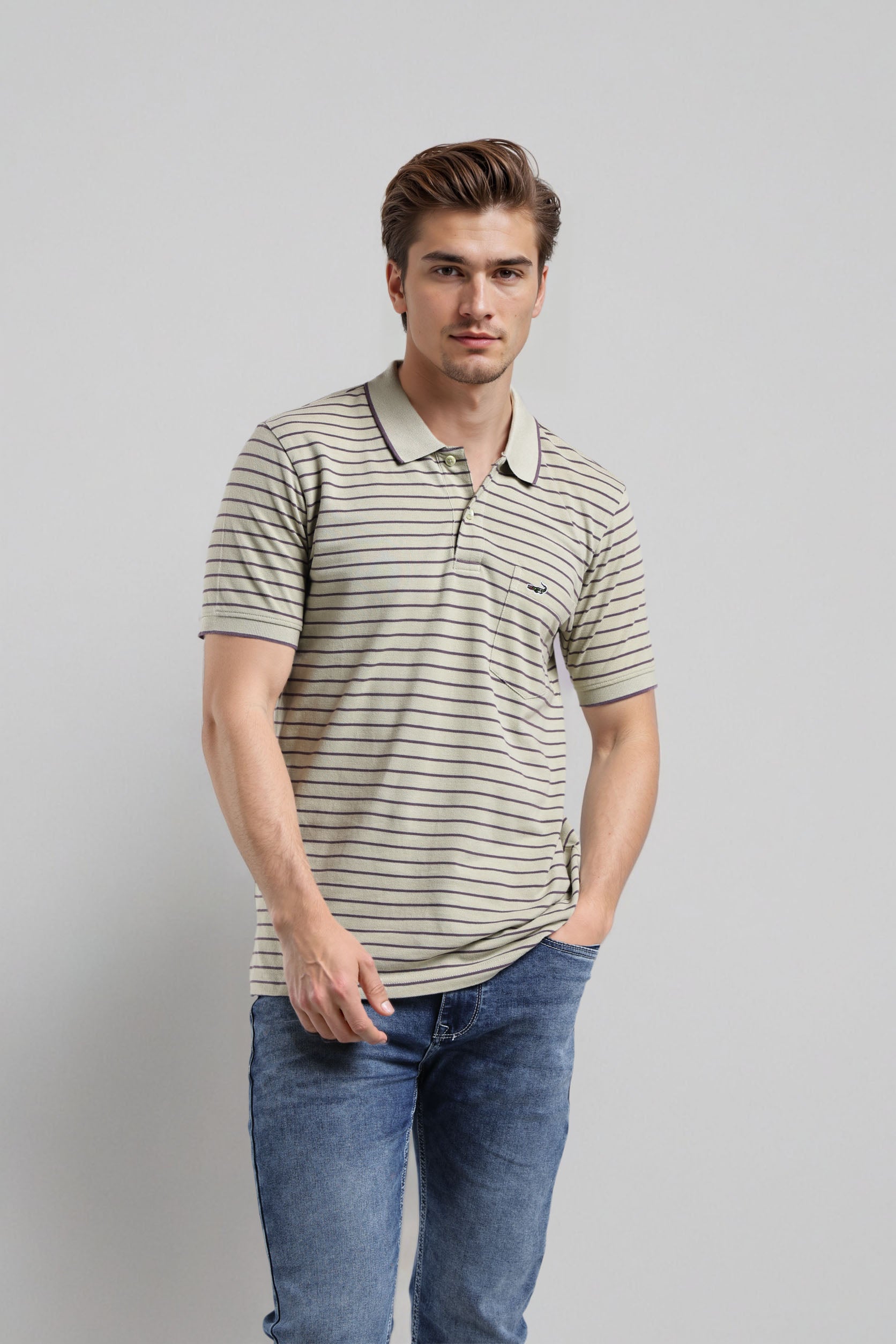 Man wearing a striped polo shirt and jeans against a plain background
