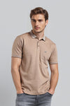 Man wearing a brown brown supima solid polo t shirt slim fit polo t shirt on a light gray background