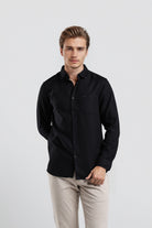 Man wearing a black shirt and beige pants on a white background