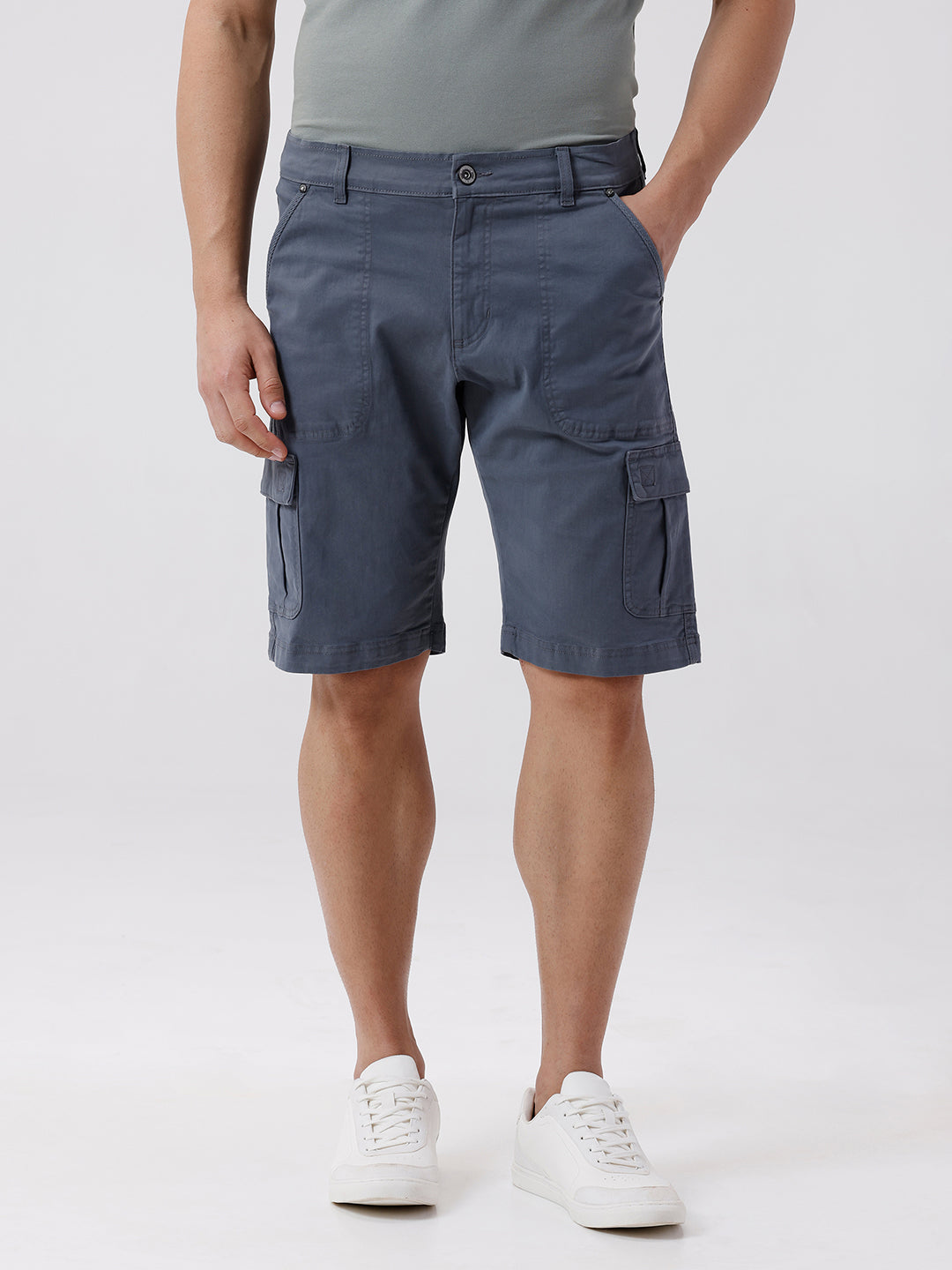Man wearing a grey garment dyed cargo shorts in dark grey with casual styling on a gray background