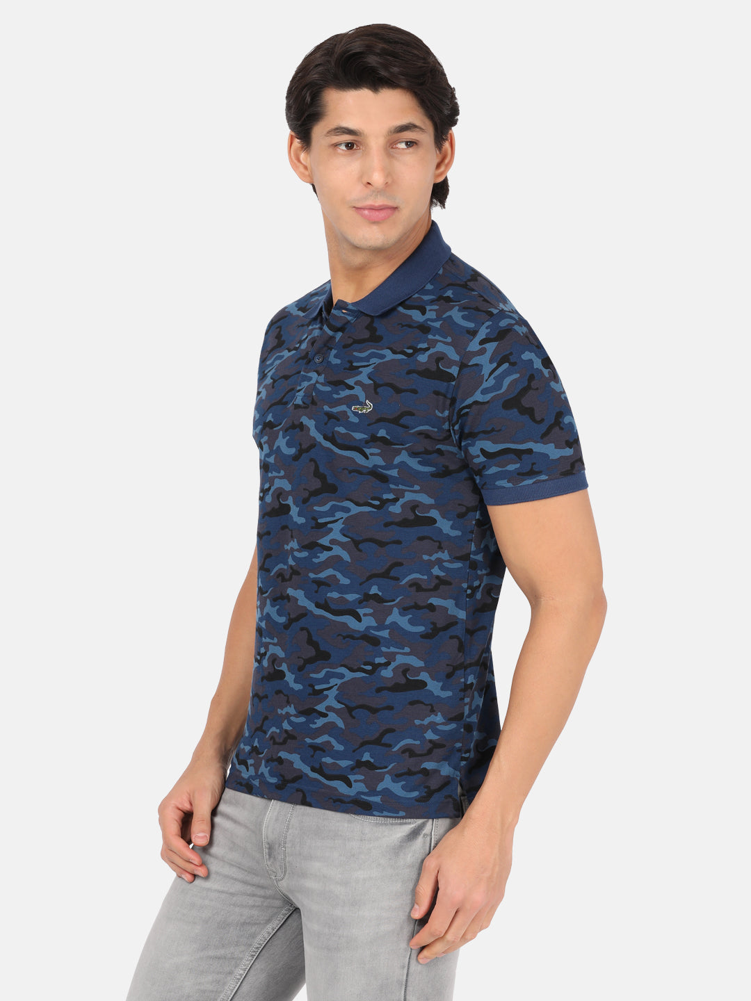 Man wearing a blue royal blue printed polo t shirt with casual styling on a gray background