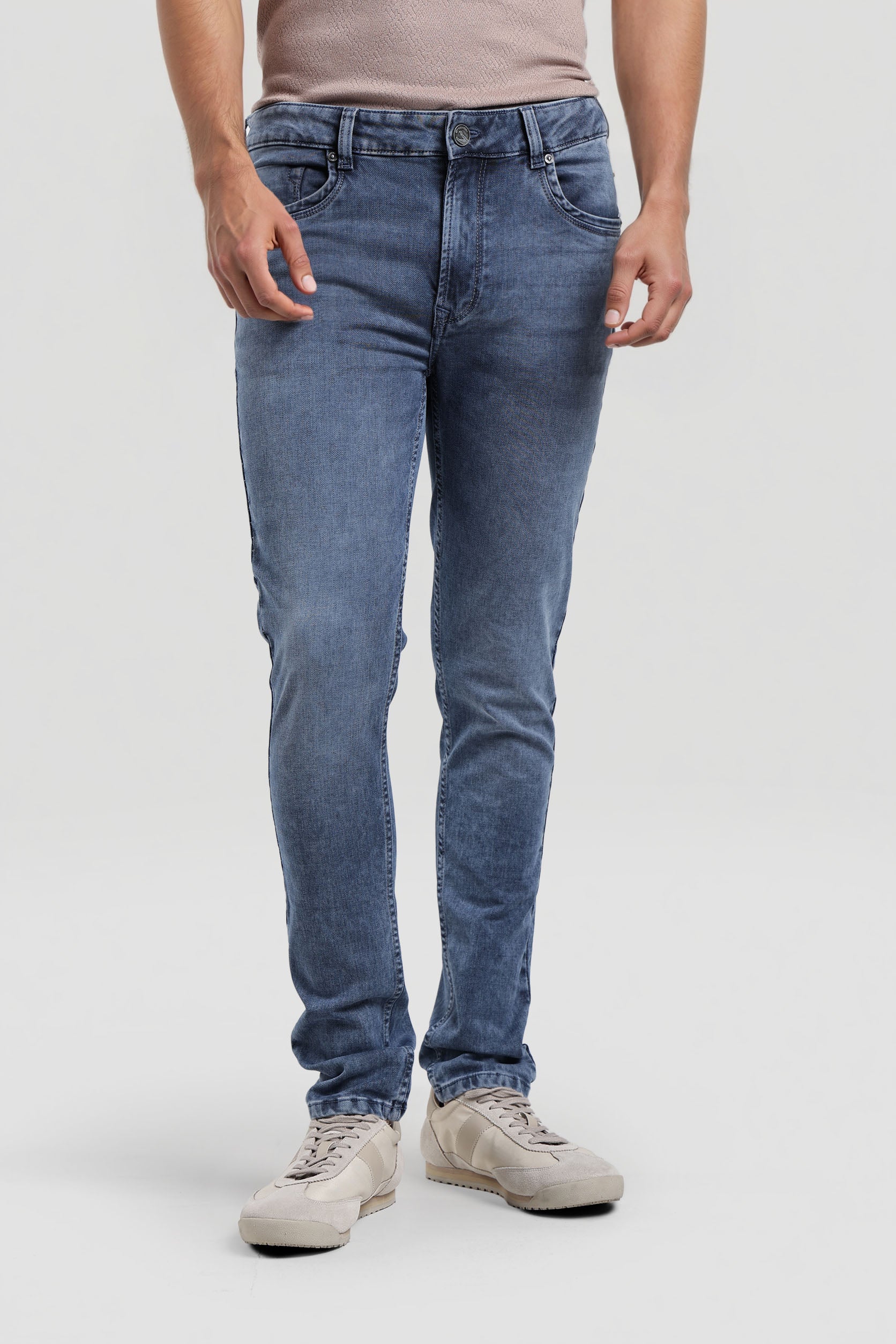 Person wearing blue jeans and beige shoes on a white background