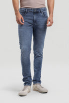 Person wearing blue jeans and beige shoes on a white background