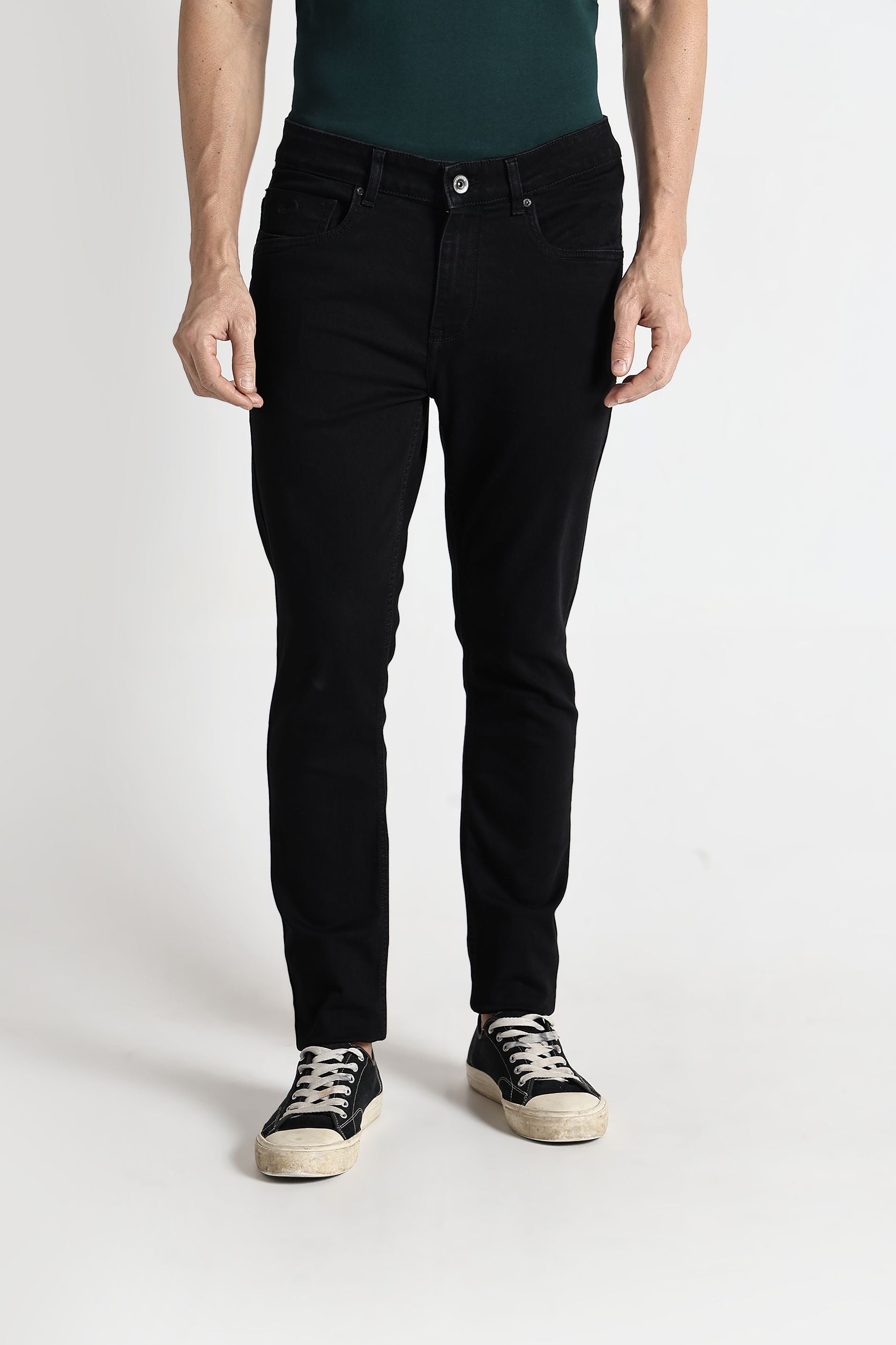 Person wearing black jeans and a green top on a white background