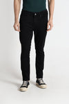 Man wearing a black black rugged appeal dark raw wash crocodile slim tappered jeans on a light gray background