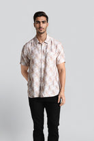 Man wearing a patterned shirt and black pants on a light gray background