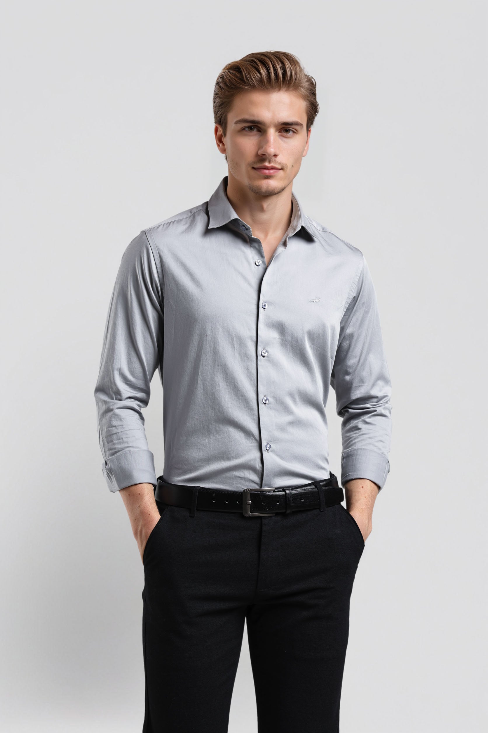 Man wearing a light gray dress shirt and black pants on a white background