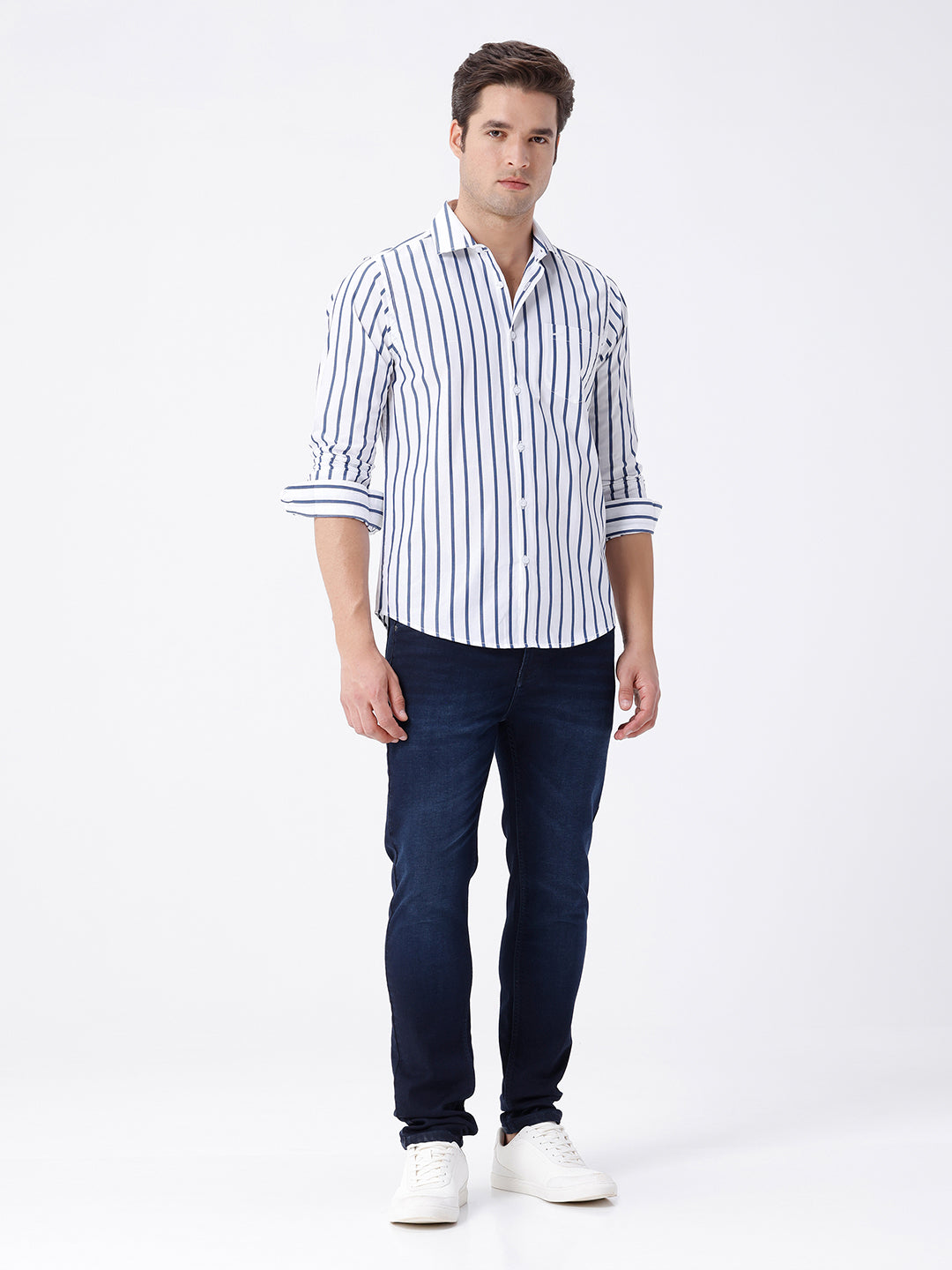 Man wearing a blue dark blue knit slim fit jeans with casual styling on a gray background