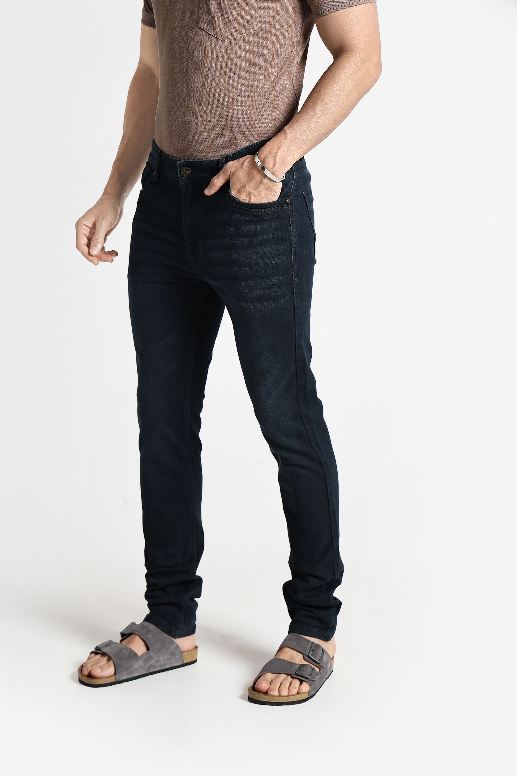 Person wearing black jeans and sandals on a white background