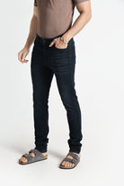 Person wearing black jeans and sandals on a white background
