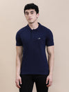 Man wearing a navy casual solid polo t shirt navy with pocket with casual styling on a gray background