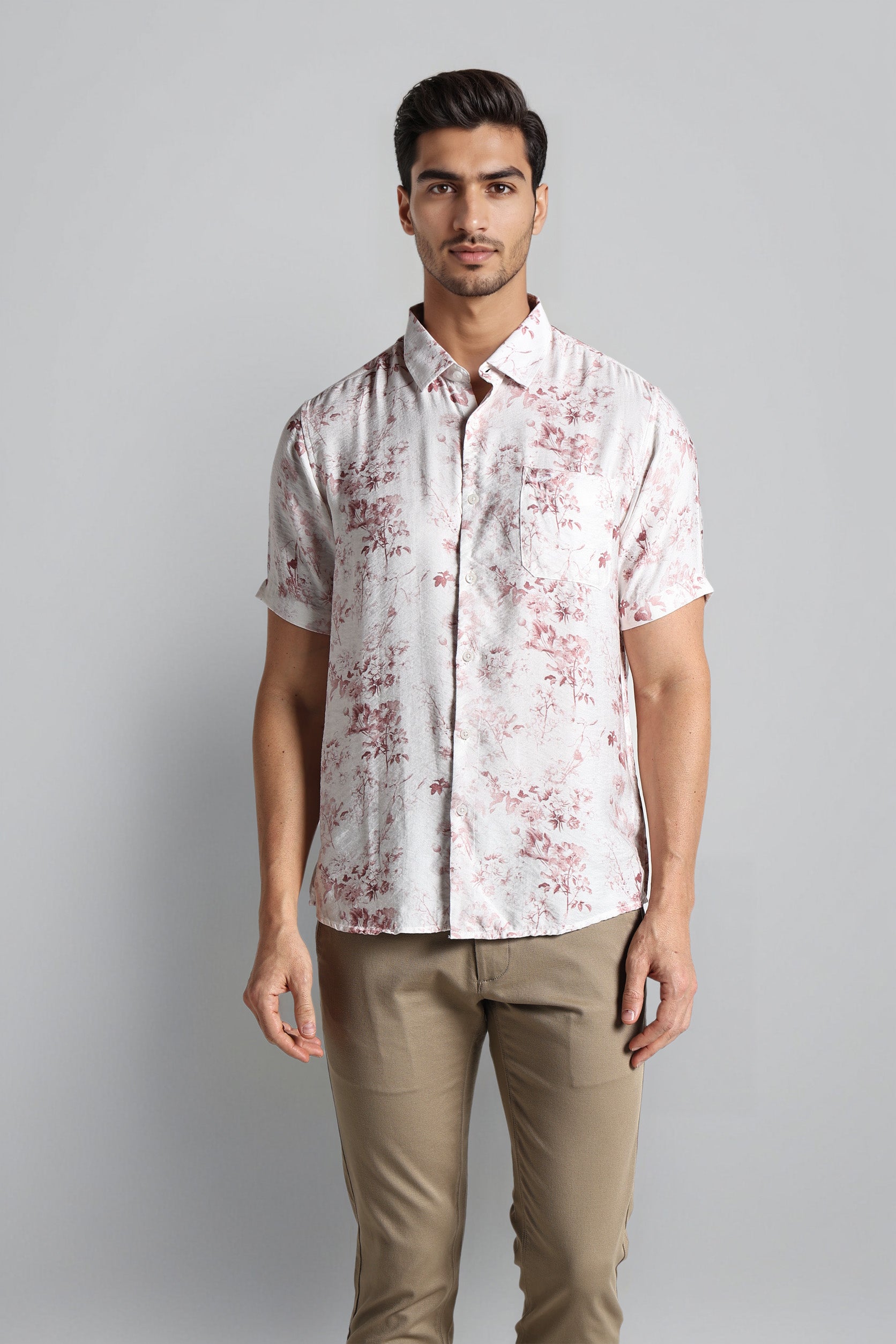 Man wearing a white patterned shirt and beige pants on a gray background