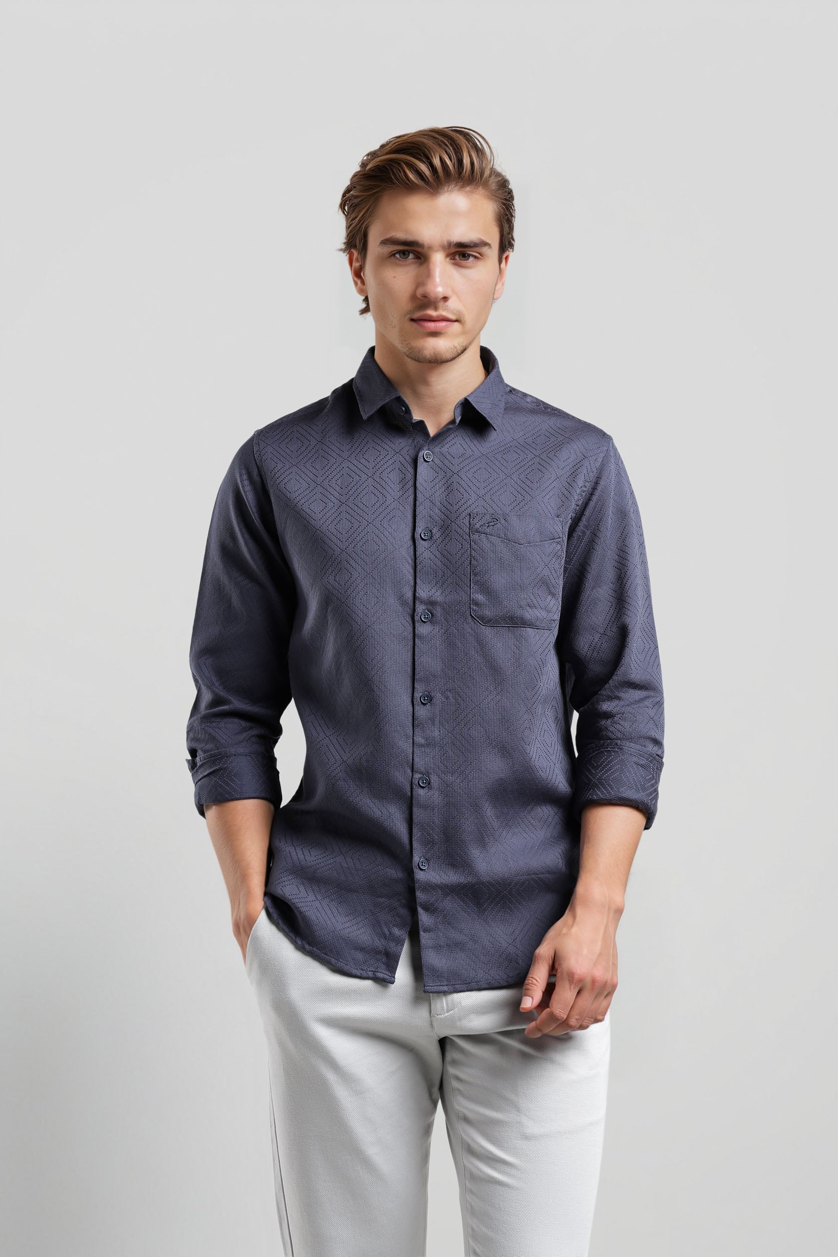 Man wearing a dark blue button-up shirt and light gray pants on a plain background