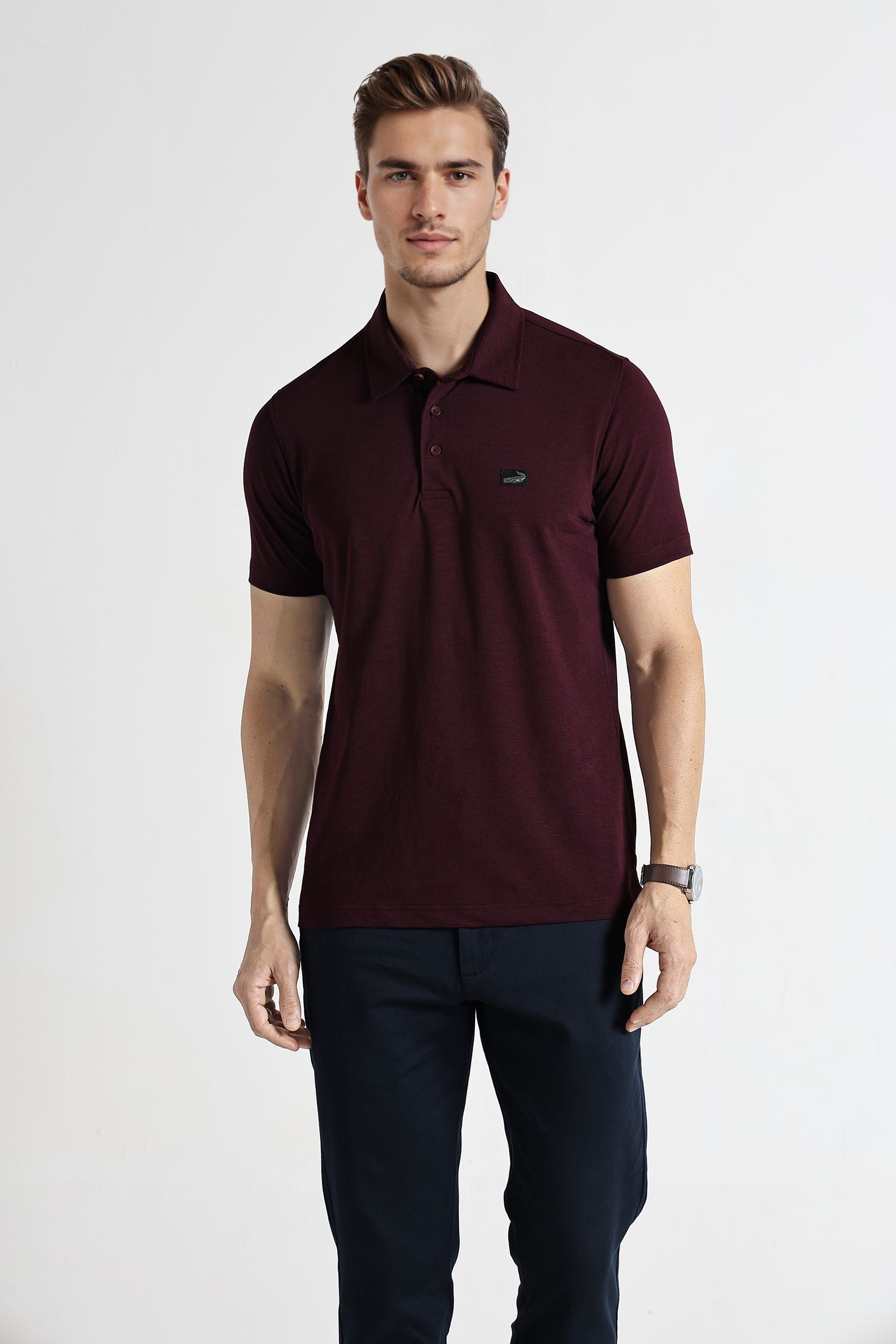 Man wearing a maroon polo shirt with a small logo on a white background