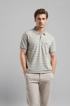 Man wearing a green green striper polo t shirt comfort fit polo t shirt on a light gray background