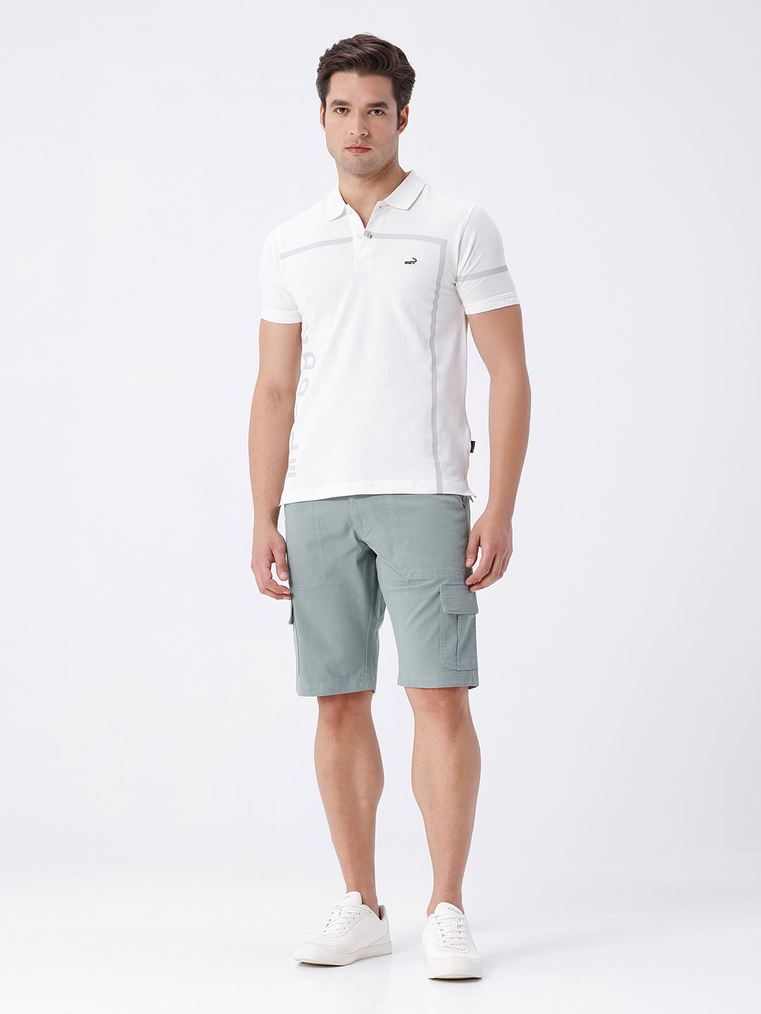 Man wearing a olive garment dyed cargo shorts in olive on a light gray background