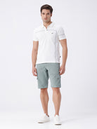 Man wearing a olive garment dyed cargo shorts in olive on a light gray background