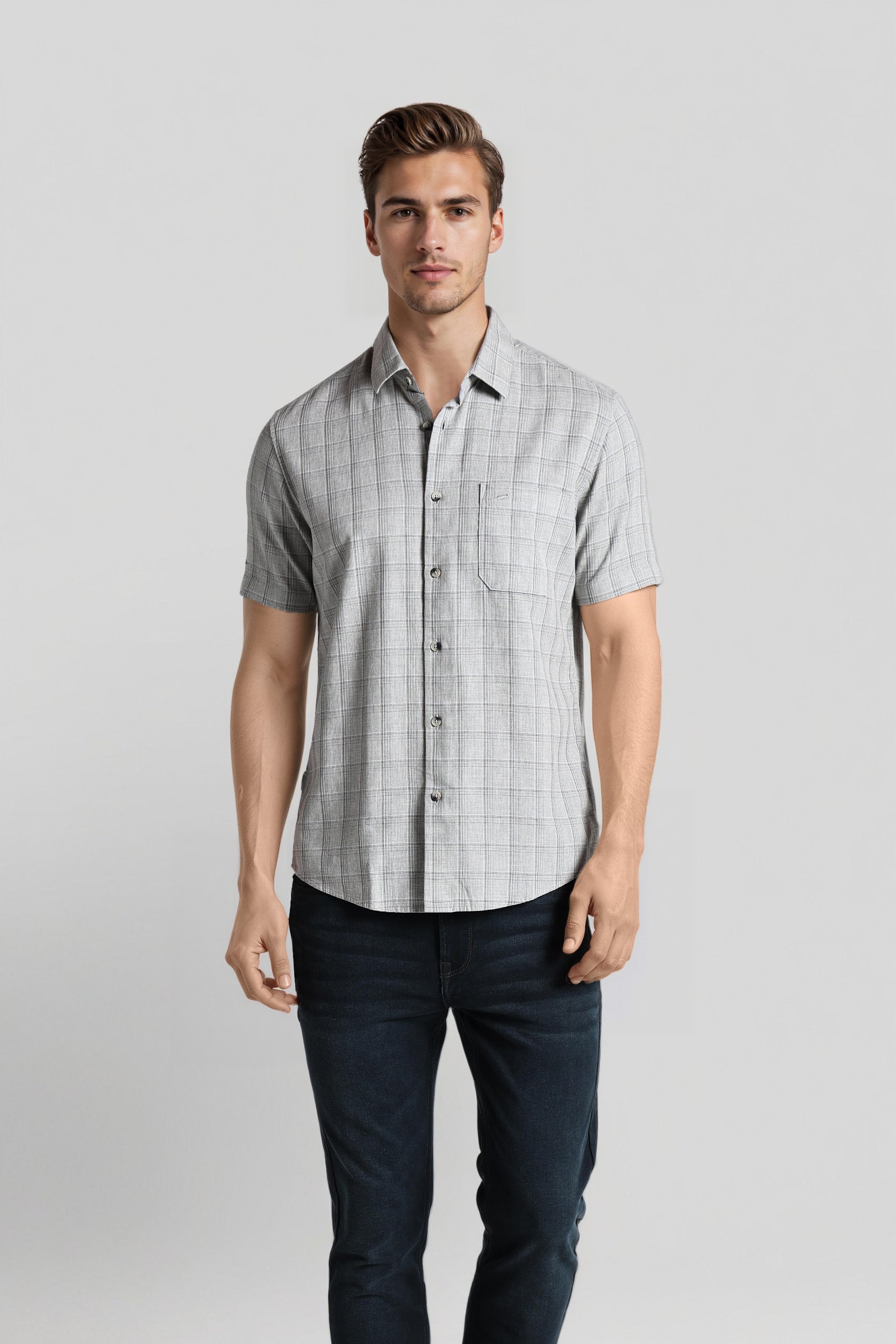 Man wearing a checkered short-sleeve shirt and dark pants on a light gray background