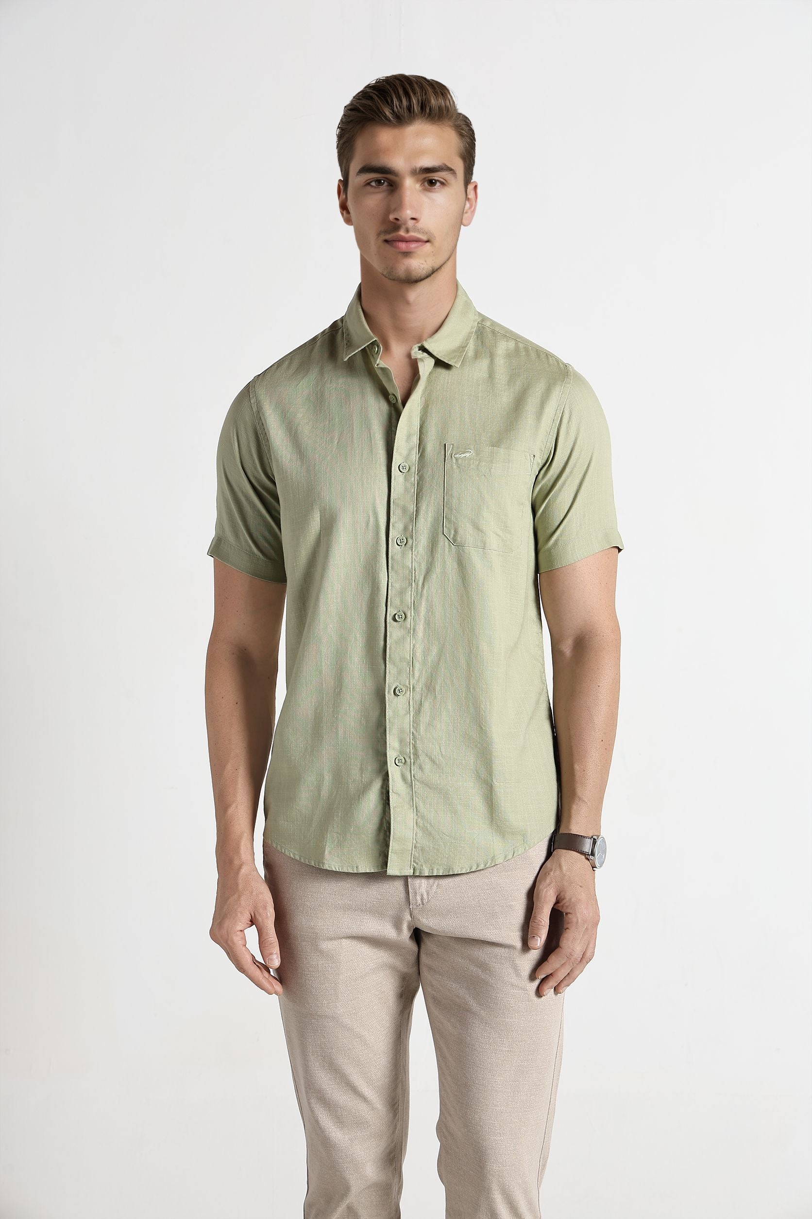 Man wearing a light green button-up shirt and beige pants on a white background