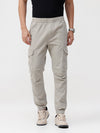 Man wearing a beige beige solid jogger fit joggers with casual styling on a gray background