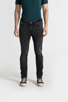 Person wearing black jeans and a green shirt on a white background