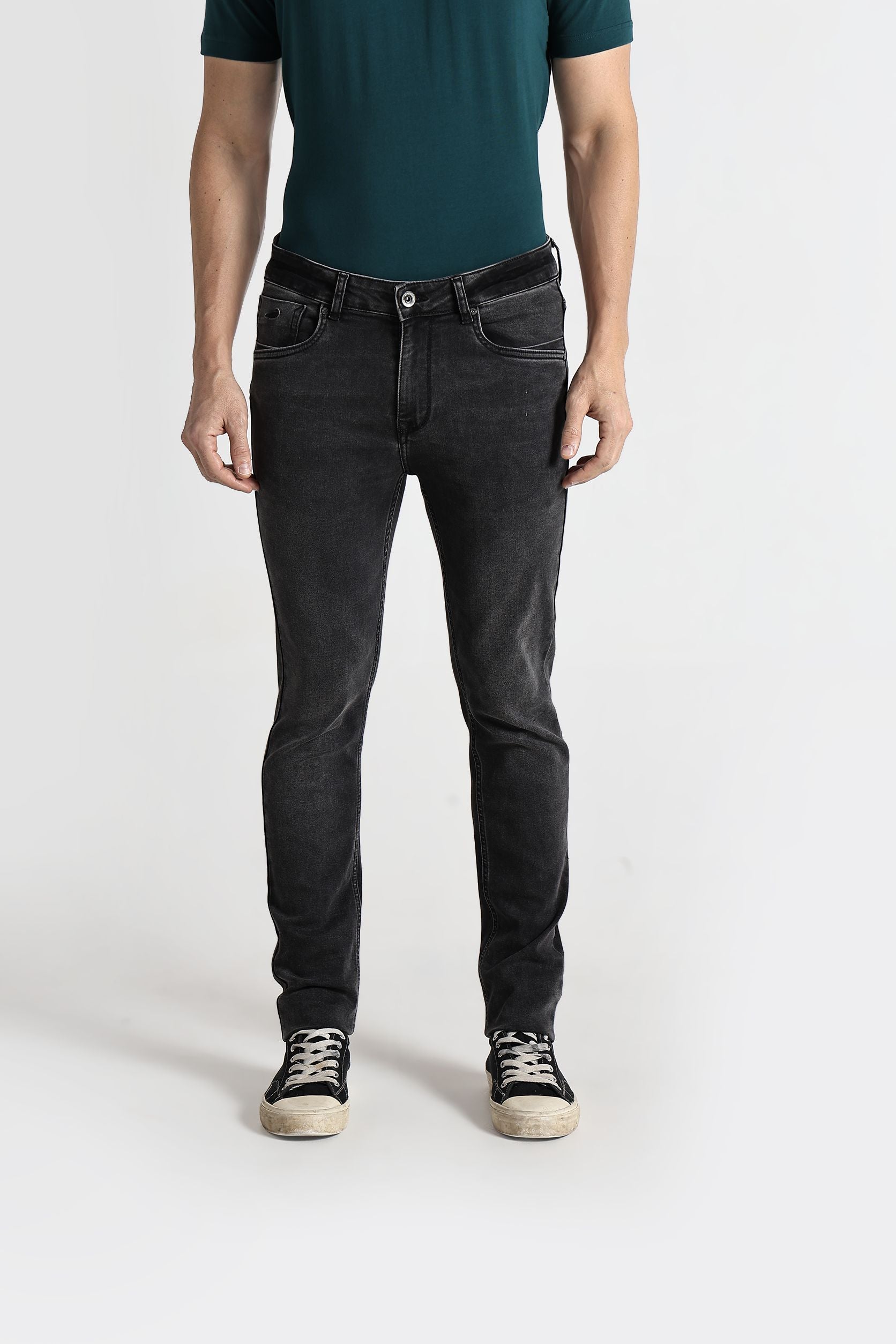 Person wearing black jeans and a green shirt on a white background