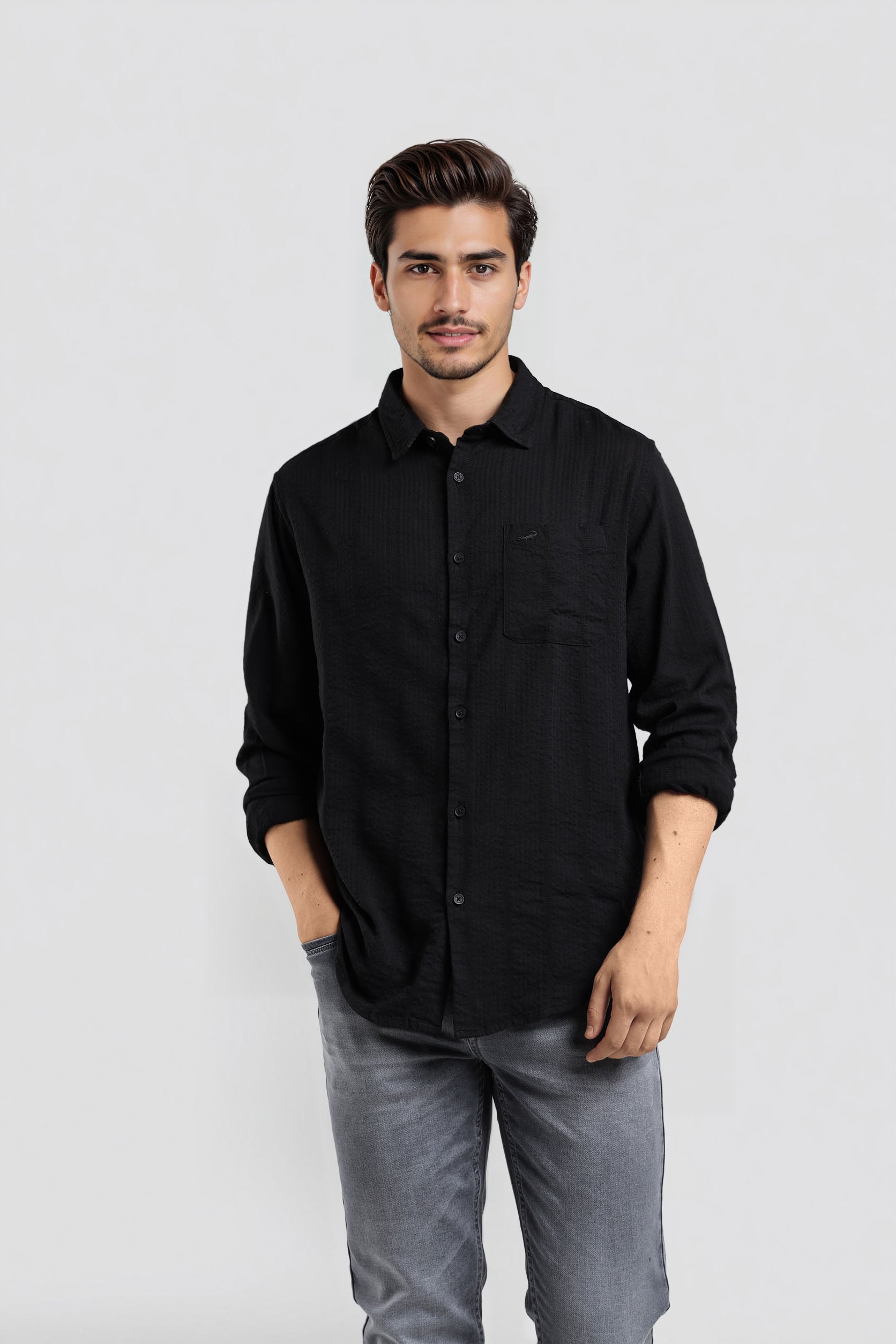 Man wearing a black shirt and gray pants against a white background