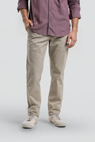 Person wearing a purple button-up shirt and beige pants on a white background