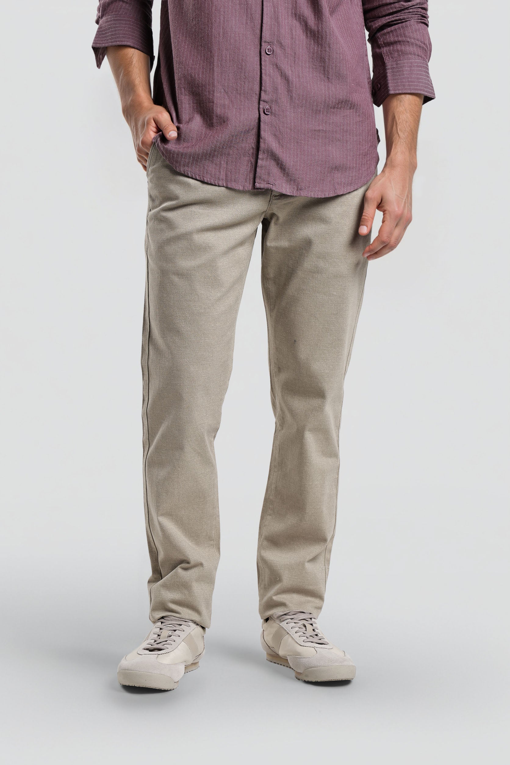 Person wearing a purple button-up shirt and beige pants on a white background