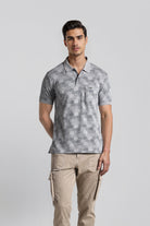 Man wearing a patterned gray polo shirt and beige pants on a light gray background