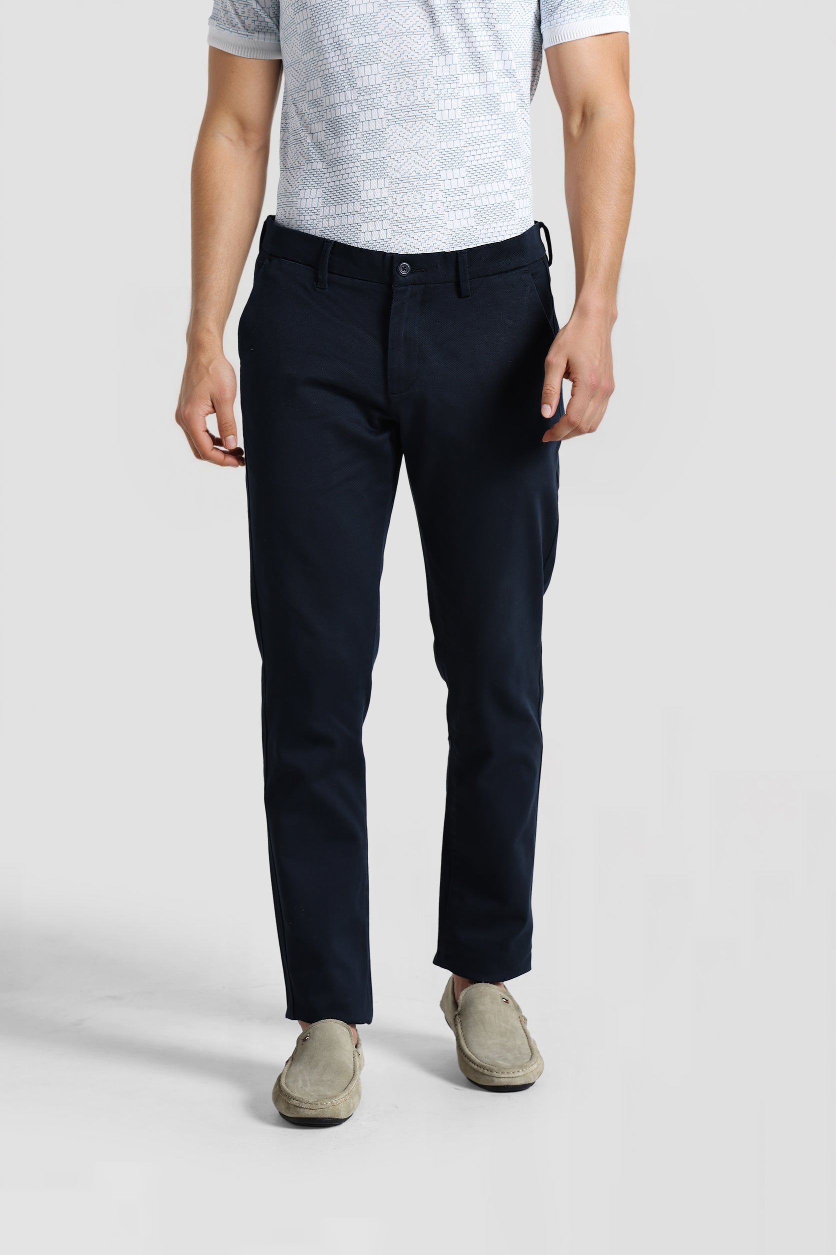 Person wearing navy pants and a gray shirt on a white background