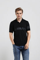 Man wearing a black polo shirt with a logo on a light gray background